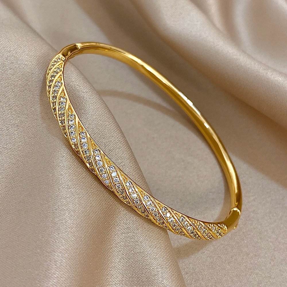 Lyxigt Vridet Manschettarmband i Guld med Zirkoner